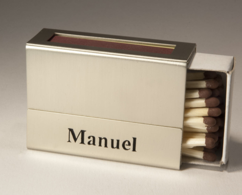 Eine Streichholzschachtel-Hülle mit dem ausgesägten Namen "Manuel"