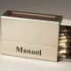 Eine Streichholzschachtel-Hülle mit dem ausgesägten Namen "Manuel"